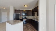 This single-floor residence at 4515 Desantis Ct in Columbus, Ohio offers a thoughtfully designed layout with modern finishes throughout. The kitchen is a standout feature, showcasing rich dark espresso cabinetry, granite-style countertops, a textured stone tile backsplash, and black appliances including a refrigerator, range, microwave, and dishwasher. Durable wood-look flooring anchors the kitchen, which opens to a breakfast bar peninsula for convenient casual dining.

The living area is bright and welcoming, filled with natural light streaming through multiple windows dressed with blinds. Plush carpeting, neutral gray walls, and a bold accent wall contribute to a contemporary yet comfortable atmosphere. The open layout connects the living space seamlessly to the kitchen.

The bedrooms continue the neutral palette with soft carpet, generous natural light, and access to closets for ample storage. The bathroom is well-appointed with dark-framed mirrors, a light stone-look vanity countertop, dark wood cabinetry, and a full tub-shower combination with built-in shelving. Wood-look flooring in the bathroom ties the space together with the rest of the home's design aesthetic.