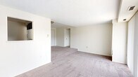 Located at 2220 High St in Cuyahoga Falls, Ohio, this 2-bedroom, 1-bathroom unit offers a practical and functional layout across a single floor. The open living area is a standout feature, filled with natural light streaming through a large floor-to-ceiling window dressed with vertical blinds, creating an airy and welcoming atmosphere. Neutral-toned carpet flows throughout the living spaces and bedrooms, lending a cohesive and clean aesthetic.

The spacious primary bedroom offers generous room for furnishings and includes a sliding-door closet with built-in shelving, providing ample storage. The second bedroom features a wide window with horizontal blinds that frames outdoor views of the surrounding neighborhood. Both bedrooms maintain a simple, neutral palette with carpeted flooring.

The kitchen is thoughtfully appointed with dark espresso cabinetry, light granite-style countertops, a double stainless steel sink, and wood-look vinyl flooring — offering a modern contrast to the rest of the unit. A hallway connects the main living areas to the bedrooms and the full bathroom, which includes a tub-shower combination, a vanity with dark cabinetry, a white countertop, and a mirrored medicine cabinet above.