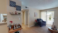 This single-floor residence offers a thoughtfully organized layout with a comfortable and functional design throughout. The living area is welcoming and well-lit, featuring carpet flooring, a sliding glass door that opens to an outdoor balcony, and vertical blinds that allow natural light to filter in. A dedicated bar cart area with wall-mounted wine glass storage adds a distinctive touch to the space.

The kitchen is efficiently designed with an L-shaped layout, featuring white cabinetry with wood trim accents, a double-basin stainless steel sink, ample counter space, and built-in appliances including a dishwasher. The light-toned countertops and textured ceiling give the kitchen a classic, practical character.

The bedrooms are carpeted and serene, each equipped with ceiling fans and closet space. The primary bedroom is notably spacious, with a bay-style window that invites natural light, a ceiling fan with integrated lighting, and a mirrored closet. A secondary bedroom offers a similarly calm atmosphere with mirrored closet doors and direct sightlines to the rest of the unit.

The bathroom is clean and well-maintained, featuring a tiled shower-tub combination with a curtain, a single vanity sink, and a large wall mirror. Textured ceilings are present throughout the unit, contributing to a consistent architectural aesthetic. The overall ambiance is cozy, practical, and move-in ready.