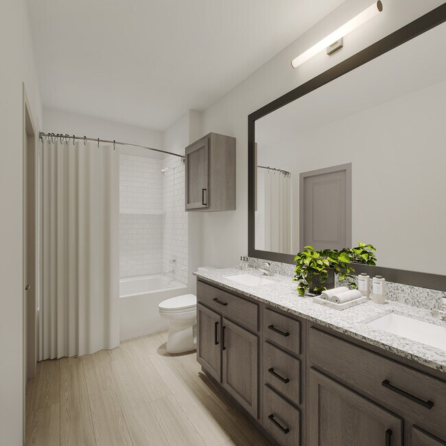 Baño moderno de Oakwood Trails con un espejo grande, un tocador elegante y una iluminación brillante para una apariencia fresca y contemporánea. - Oakwood Trails - A 62+ Community