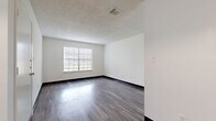 Located at 1805 IH-35 N in San Marcos, TX, this 2-bedroom, 1-bathroom unit offers a practical and well-organized single-floor layout. The living area greets you upon entry with rich, dark wood-style vinyl flooring, crisp white walls, and a textured ceiling. A pendant light and a pass-through counter connect the living space to the galley-style kitchen, which is equipped with dark cabinetry, white countertops, a stainless steel sink, and black appliances including a dishwasher and range. Both bedrooms feature plush carpeting, ceiling fans with light fixtures, and large windows fitted with blinds that allow for ample natural light. Each bedroom is paired with its own closet, one of which is a walk-in closet with dual hanging rods offering generous storage capacity. The full bathroom includes a shower-tub combination, a dark-cabinetry vanity with a white countertop, and wood-style flooring. Throughout the unit, consistent use of dark trim, vinyl plank flooring in the common areas, and neutral tones create a cohesive and functional living environment.