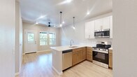 Located at 5176 Old Town Hall Road in Eau Claire, Wisconsin, this well-appointed one-bedroom, one-bathroom residence offers a thoughtfully designed single-floor layout with modern finishes throughout. Light-toned hardwood-style flooring flows seamlessly across the entire space, creating a cohesive and inviting atmosphere.

The open-concept kitchen and living area serves as the heart of the home. The kitchen features white shaker-style upper cabinets paired with warm wood-tone lower cabinets, white quartz countertops, a peninsula with an undermount sink, and a full suite of stainless steel appliances including a gas range, over-the-range microwave, and refrigerator. The adjoining living room is bright and airy, equipped with a ceiling fan and open sightlines.

The generously sized bedroom receives abundant natural light through dual windows overlooking lush greenery, and includes a ceiling fan for added comfort. A standout feature is the sliding barn-door closet, which opens to a spacious walk-in closet outfitted with white wire shelving and hanging rods on multiple walls.

The bathroom is clean and functional, featuring a tub-shower combination with white tile surround, a wood-tone vanity with white countertop, and brushed gold accent hardware. The overall design is modern, neutral, and move-in ready.
