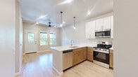 Located at 5176 Old Town Hall Road in Eau Claire, Wisconsin, this well-appointed one-bedroom, one-bathroom residence offers a thoughtfully designed single-floor layout with modern finishes throughout. Light-toned hardwood-style flooring flows seamlessly across the entire space, creating a cohesive and inviting atmosphere.

The open-concept kitchen and living area serves as the heart of the home. The kitchen features white shaker-style upper cabinets paired with warm wood-tone lower cabinets, white quartz countertops, a peninsula with an undermount sink, and a full suite of stainless steel appliances including a gas range, over-the-range microwave, and refrigerator. The adjoining living room is bright and airy, equipped with a ceiling fan and open sightlines.

The generously sized bedroom receives abundant natural light through dual windows overlooking lush greenery, and includes a ceiling fan for added comfort. A standout feature is the sliding barn-door closet, which opens to a spacious walk-in closet outfitted with white wire shelving and hanging rods on multiple walls.

The bathroom is clean and functional, featuring a tub-shower combination with white tile surround, a wood-tone vanity with white countertop, and brushed gold accent hardware. The overall design is modern, neutral, and move-in ready.