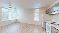 Located at 2133 North Argyle Street in Portland, Oregon, this two-bedroom, one-bathroom unit offers a well-organized single-floor layout designed for efficient, comfortable living. Light hardwood-style flooring runs throughout, lending a clean and cohesive look to every room.

The combined kitchen and living area serves as the heart of the unit. The kitchen is outfitted with rich dark wood cabinetry, light countertops, a stainless steel sink, and white appliances including a refrigerator, electric range, and dishwasher. Recessed lighting brightens the space, while a window brings in natural light. The adjacent living area features a ceiling fan and a large corner window arrangement that floods the room with daylight and offers views of the surrounding Portland neighborhood.

The primary bedroom is a comfortable, well-proportioned room with a ceiling fan, a built-in closet with shelving, and access to the hallway. The second bedroom also includes a ceiling fan and built-in closet space, maintaining consistent finishes throughout. Both bedrooms benefit from the unit's clean, neutral palette.

The bathroom is straightforward and functional, featuring a full tub-shower combination, toilet, and vanity with light hardwood-style flooring continuing from the rest of the unit. A hallway and dedicated closet provide additional storage throughout this efficiently designed Portland home.