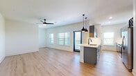 This well-designed single-story home offers three bedrooms, two bathrooms, and a thoughtfully laid-out floor plan that maximizes comfort and functionality. Light-toned hardwood flooring flows consistently throughout the entire space, complementing the crisp white walls and clean modern aesthetic.

The open-concept kitchen and living room serve as the heart of the home. The kitchen features gray shaker-style cabinetry with matte black hardware, white quartz countertops, a subway tile backsplash, stainless steel appliances including a French door refrigerator and range, and a peninsula with a sink and pendant lighting above. The adjoining living area is bright and spacious, fitted with a ceiling fan and multiple windows with blinds that invite generous natural light, plus direct access to an outdoor area via a glass-paneled door.

A central hallway connects the bedrooms and bathrooms, lined with stylish gray panel doors and recessed lighting. Each bedroom is well-proportioned, featuring ceiling fans, windows with outdoor views, and ample closet access. The generously sized primary bedroom includes its own private bathroom, which showcases a dual-sink vanity with gray cabinetry, a large framed mirror, modern light fixtures, and a marble-tiled shower. A dedicated laundry room and three closets round out the practical amenities of this move-in ready home.
