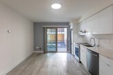 Located on College Avenue in the heart of Berkeley, CA, this two-bedroom, one-bathroom unit offers a thoughtfully designed single-floor layout with a clean, contemporary aesthetic throughout. Light wood-style flooring runs continuously across the living areas and bedrooms, creating a bright and cohesive feel.

The kitchen is a standout feature, outfitted with high-gloss white cabinetry extending to the ceiling, a marble-veined quartz backsplash and countertops, a stainless steel sink, and stainless steel appliances including a range, dishwasher, and range hood. A sliding glass door adjacent to the kitchen leads to a private balcony, filling the space with natural light and providing outdoor access.

The open living area flows naturally from the kitchen and benefits from recessed lighting and a large window that frames outdoor views. Both bedrooms are comfortably proportioned, with the primary bedroom offering generous closet space via a sliding-door built-in with double hanging rods and shelving. An in-unit washer and dryer is conveniently accessible from the primary bedroom area.

The bathroom features a full tub-shower combination with clean white tile surround and modern fixtures. A connecting hallway ties the layout together efficiently, completing this well-appointed and move-in-ready Berkeley residence.