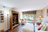 This well-appointed one-bedroom, one-bathroom unit at 1300 S Elmhurst Rd in Mount Prospect, IL offers a thoughtfully organized single-floor layout that maximizes every square foot. The living room serves as the heart of the home, featuring rich hardwood flooring and a large sliding glass door that floods the space with natural light while offering pleasant outdoor views of the surrounding greenery. A dedicated seating area provides a welcoming and functional environment for relaxing or entertaining.

The kitchen is efficiently designed with warm oak cabinetry, granite countertops, a classic white subway tile backsplash, and stainless steel appliances including a dishwasher and gas range. White tile flooring adds a clean, bright contrast to the warm wood tones. An open pass-through connects the kitchen seamlessly to the living area.

The bedroom is a serene retreat, finished with soft wall-to-wall carpeting and accented by light blue walls that create a calm atmosphere. A window allows for natural light, complemented by ample space for furnishings. An adjacent full bathroom features a tiled soaking tub and shower combination with tasteful detailing and sage green accent walls.

A hallway connects the rooms efficiently, and a dedicated closet provides valuable storage. Overall, the unit presents a cozy, functional living space with a warm and inviting ambiance.