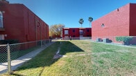 Located at 4322 Kostoryz Rd in Corpus Christi, Texas, this single-floor unit is part of a distinctive multi-unit complex characterized by its striking red brick exterior, decorative arched details, and lush green grounds framed by a chain-link fence and accented by mature palm trees. The property's bold architectural presence is immediately recognizable and set against the sunny South Texas sky.

Inside, the unit features light wood-look laminate flooring throughout, creating a clean and cohesive aesthetic. The open living area is bright and airy, bathed in natural light streaming through wide vertical blinds, and features a textured popcorn ceiling that adds classic character. The layout flows naturally from the entry toward a well-organized galley-style kitchen, which is equipped with white cabinetry, black appliances including a range and refrigerator, a built-in range hood, and a double sink — offering a functional and efficient cooking space.

The bathroom is neatly appointed with white cabinetry, a single vanity with a granite-style countertop, a framed mirror, and updated fixtures, all set on matching light wood-look flooring. The unit includes a private entry door with dual locks, providing added security. Overall, the space presents a clean, well-maintained interior with a neutral color palette, making it a practical and comfortable setting in a vibrant Corpus Christi neighborhood.