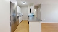 Located at 565 Talbot St in London, Ontario, this one-bedroom, one-bathroom unit offers a thoughtfully designed single-floor layout with a clean, modern aesthetic. Light-toned hardwood flooring runs throughout the entire space, creating a warm and cohesive feel from room to room.

The open-concept living and kitchen area forms the heart of the unit. The kitchen is outfitted with white cabinetry, a stainless steel refrigerator, a dishwasher, white subway tile backsplash, and a peninsula with a grey countertop that provides both additional workspace and a casual dining option. The living area is bright and airy, benefiting from a large sliding glass door that opens to a private balcony, allowing natural light to fill the space and offering views of the surrounding greenery.

The bedroom is a well-proportioned, quiet retreat featuring a built-in closet with bifold doors, soft grey walls, and a window that brings in additional natural light. Baseboard heating is present in both the living area and bedroom.

The bathroom is finished in a clean, all-white palette, featuring a tiled tub-shower combination, large-format floor tiles, and a vanity with a grey countertop. Neutral grey walls and white trim throughout the unit contribute to a bright, move-in-ready atmosphere.