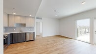 Located at 1855 Westwood Blvd in Los Angeles, this modern single-floor residence offers a clean, contemporary design throughout. The open-concept living and kitchen area is anchored by warm light wood flooring that extends seamlessly through the main spaces, creating a cohesive and inviting atmosphere. Recessed lighting and crisp white walls enhance the sense of brightness throughout.

The kitchen is well-appointed with a full suite of stainless steel appliances, including a French door refrigerator, range, microwave, and dishwasher. Cabinetry combines white upper cabinets with dark wood-toned lower cabinets, complemented by a subtle tile backsplash and ample counter space, offering both style and functionality.

The bedrooms are generously sized and filled with natural light, thanks to large floor-to-ceiling windows and sliding glass doors that frame views of the surrounding Los Angeles neighborhood, including glimpses of palm trees and the cityscape. The airy, neutral palette of each room provides a versatile canvas.

Two bathrooms feature a consistent design language, with large-format beige tile flooring, white subway-tiled tub-shower combinations, matte black fixtures, and clean-lined vanities with modern hardware. The overall ambiance of this residence is modern, bright, and move-in ready.