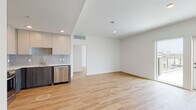 Located at 1855 Westwood Blvd in Los Angeles, this modern single-floor residence offers a clean, contemporary design throughout. The open-concept living and kitchen area is anchored by warm light wood flooring that extends seamlessly through the main spaces, creating a cohesive and inviting atmosphere. Recessed lighting and crisp white walls enhance the sense of brightness throughout.

The kitchen is well-appointed with a full suite of stainless steel appliances, including a French door refrigerator, range, microwave, and dishwasher. Cabinetry combines white upper cabinets with dark wood-toned lower cabinets, complemented by a subtle tile backsplash and ample counter space, offering both style and functionality.

The bedrooms are generously sized and filled with natural light, thanks to large floor-to-ceiling windows and sliding glass doors that frame views of the surrounding Los Angeles neighborhood, including glimpses of palm trees and the cityscape. The airy, neutral palette of each room provides a versatile canvas.

Two bathrooms feature a consistent design language, with large-format beige tile flooring, white subway-tiled tub-shower combinations, matte black fixtures, and clean-lined vanities with modern hardware. The overall ambiance of this residence is modern, bright, and move-in ready.