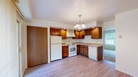 Located at 1862 S Stone Maple Ln in Elkhart, Indiana, this single-floor, 3-bedroom, 1-bathroom home offers a practical and efficiently organized layout. The kitchen serves as a functional centerpiece, featuring warm wood cabinetry with ample storage, light laminate wood flooring, a full suite of white appliances including a refrigerator, electric range with overhead ventilation hood, and dishwasher. Recessed lighting and a hanging chandelier illuminate the space, which opens toward additional living areas. The three bedrooms are carpeted and finished with neutral tones, offering a clean, move-in-ready feel. Each room features windows with blinds that allow natural light and outdoor views of the surrounding greenery. The primary bedroom provides a comfortable amount of space, with wood-toned closet doors adding warmth. The full bathroom includes a tiled tub-shower combination with an accent border, a wood-cabinet vanity with a single sink, and light flooring that ties the room together. A dedicated laundry room with built-in shelving and light wood flooring accommodates full-size washer and dryer units, adding everyday convenience to this compact yet well-appointed home.