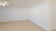 Located at 1860 SW 68th Ave in Miramar, FL, this 1-bedroom, 1-bathroom residence offers a compact and efficiently designed single-floor layout. Light-colored ceramic tile flooring runs consistently throughout the entire unit, creating a cohesive and easy-to-maintain interior. The combined living and dining area serves as the central gathering space, featuring a ceiling fan with light fixture, a wall-mounted A/C unit, and a window that brings in natural light. A modern ring-style pendant chandelier distinguishes the dining area and adds a contemporary touch to the otherwise clean, minimalist aesthetic. The kitchen is bright and functional, equipped with white cabinetry, a smooth-top electric range, over-the-range microwave, refrigerator, and a window with blinds overlooking the outdoors. A hallway connects the living areas to the private spaces and is accented by a second ring pendant light fixture. The spacious bedroom includes a ceiling fan, a wall A/C unit, a window with natural light, and a closet with double panel doors. The bathroom features full-height beige tile surround on the tub/shower combo and a small window for ventilation. Throughout the unit, bright white walls and natural light contribute to an open and airy atmosphere.