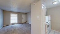 This 1-bedroom, 1-bathroom unit offers a practical and efficient single-floor layout designed to maximize every square foot. The living room greets you at the entrance, featuring neutral-toned carpet, a large window that brings in natural light, and a textured ceiling — a consistent design element throughout the unit. The space flows toward a tiled transition area, connecting to the rest of the home. The galley-style kitchen is efficiently arranged, featuring white cabinetry, white appliances including a range and refrigerator, a double sink, light countertops, and a peninsula-style overhang ideal for casual dining. White tile flooring runs through the kitchen and bathroom, maintaining a clean, cohesive aesthetic. The bedroom is a well-proportioned retreat with plush carpet, a ceiling fan with light, a window with an exterior view, and access to a spacious walk-in closet outfitted with dual hanging rods and built-in shelving for ample storage. The bathroom is straightforward and functional, with tile flooring and an adjoining access panel. Throughout the unit, ceiling fans are present in multiple rooms, neutral wall tones provide a versatile backdrop, and the textured ceilings add a classic residential character to the overall space.