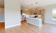 Located at 4362 Watermark Dr in Wilmington, NC, this modern single-story home offers 1,210 square feet of thoughtfully designed living space across 3 bedrooms and 2 bathrooms. The open-concept kitchen and living area features light wood cabinetry extending to the ceiling, white quartz countertops, a subway tile backsplash, stainless steel appliances including a French door refrigerator, and a central island — all set on durable light wood flooring. The living area is bathed in natural light from expansive windows and a glass door leading to a private balcony, which showcases breathtaking panoramic views of the waterway and surrounding landscape. The primary bedroom spans 160 square feet with plush carpeting, a ceiling fan, and serene outdoor views. It connects to a spacious walk-in closet with built-in shelving and rod systems. The en-suite bathroom features a sleek walk-in shower with a matte black framed glass door, warm wood vanity cabinetry, and wood-look flooring. A second full bathroom includes a soaking tub/shower combo with matte black fixtures. Additional bedrooms offer carpet flooring, ceiling fans, and natural light. A hallway connects all rooms, with two closets providing ample storage throughout this clean, contemporary residence.