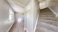 Located at 4 Valley Brook Cir in Rochester, NY, this multi-floor home offers two bedrooms, two bathrooms, and a functional layout spread across three levels. The main floor features a bright, open living room with light hardwood-style flooring and a sliding glass door that fills the space with natural light and provides outdoor access. The updated kitchen is thoughtfully designed with crisp white cabinetry, subway tile backsplash, quartz-style countertops, stainless steel appliances including a dishwasher and range, and a window that brings in additional natural light. The upper floor houses two carpeted bedrooms, both finished in a neutral palette. The primary bedroom is generously sized and features dual bi-fold closets, offering ample storage. The second bedroom includes its own closet as well. Two bathrooms serve the home — one with a clean vanity and wood-look flooring, and another featuring a full tub-shower combination with brushed nickel fixtures. The lower level contains an unfinished utility space with exposed framing and concrete walls, presenting versatile potential. A staircase connects all three levels, completing this well-structured home.