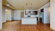 This single-floor residence offers a thoughtfully designed layout that balances functionality with style. The open-concept kitchen and living area forms the heart of the space, anchored by a large peninsula with granite countertops and an integrated sink. Rich, dark espresso-toned cabinetry lines the kitchen walls, complemented by a decorative mosaic tile backsplash and a full suite of stainless steel appliances, including a gas range, built-in microwave, and refrigerator. Pendant lighting and track lighting illuminate the space, adding warmth and depth. Durable hardwood-style flooring extends through the kitchen and main living areas, creating a seamless and easy-to-maintain surface. The living area benefits from natural light through large windows fitted with blinds, and a ceiling fan adds comfort overhead. The bedrooms feature plush carpeting, generous windows with outdoor views, and access to a spacious walk-in closet outfitted with multi-level shelving and hanging rods. The bathroom maintains the same design language as the kitchen, featuring a dark wood vanity with granite countertop and tile flooring. Crown molding throughout the unit adds an elevated architectural detail, tying together the cohesive and polished aesthetic of the space.