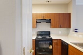Located at 9721 Summit Circle in Upper Marlboro, MD, this one-bedroom, one-bathroom single-floor home offers a well-designed layout with a warm, neutral palette throughout. The combined kitchen and living room serves as the heart of the home, featuring plush carpeting, crown molding, and a classic fireplace with a white mantel and sleek black surround — a standout centerpiece for the space. Natural light filters in through multiple windows, providing views of the surrounding greenery. The kitchen is thoughtfully separated by a half-wall pass-through, featuring warm wood cabinetry, a skylight, and stainless steel appliances, creating an efficient and functional cooking area. The bedroom offers a comfortable and well-proportioned retreat, with soft carpeting, a large window overlooking the private deck and landscaped exterior, and direct access to the bathroom and in-unit laundry room. The bathroom includes a generously sized vanity with ample cabinetry. A dedicated laundry area with a full-size washer and dryer adds significant everyday convenience. The private deck looks out over a landscaped yard with mature shrubs and trees, offering a quiet outdoor escape in a residential neighborhood setting.