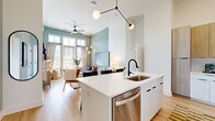 Located in Charlotte's vibrant Dilworth neighborhood, this three-bedroom, two-bathroom single-floor residence offers a thoughtfully designed open-concept layout with modern finishes throughout. Light hardwood flooring flows seamlessly across the entire space, creating a cohesive and airy feel.

The kitchen is a standout feature, showcasing a large white quartz waterfall island with an undermount sink and matte black faucet, two-tone cabinetry combining white lower cabinets with warm wood-tone uppers, and a full suite of stainless steel appliances including a range, microwave, and French door refrigerator. The kitchen opens directly into the living area, which is anchored by sage green accent walls, soaring ceilings, and floor-to-ceiling windows and doors that flood the space with natural light.

The primary bedroom is generously proportioned, featuring tall ceilings, large windows with exterior views, and direct access to a well-appointed en-suite bathroom with a walk-in glass shower, white floating vanity, and matte black fixtures. The second bathroom offers a clean, minimalist design with a tub-shower combo and equally refined finishes.

Two additional bedrooms provide flexible use, each benefiting from the home's bright, open atmosphere. A dedicated entrance, hallway, and closet complete the well-organized floor plan, making this a highly functional and stylish Charlotte residence.