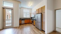 Located at 1596 Stuart St in Denver, Colorado, this single-floor residence offers a well-designed layout with contemporary finishes throughout. The kitchen is a standout feature, boasting warm-toned wood cabinetry, dark granite countertops, and a mosaic tile backsplash that adds visual texture. A full suite of stainless steel appliances — including a refrigerator with ice maker, electric range, built-in microwave, and dishwasher — makes this kitchen both functional and stylish. Light wood-style flooring runs through the kitchen, complementing the bright, neutral walls and enhancing the open feel of the space. Natural light filters in through a window fitted with blinds, keeping the kitchen airy and inviting. The bedrooms feature plush carpeting and notably tall ceilings that amplify the sense of space. One bedroom includes a walk-in closet with built-in shelving, while another benefits from a trio of tall windows that flood the room with natural light and offer views of the surrounding neighborhood. The bathroom is clean and functional, featuring a tiled tub-and-shower combination, a wood-cabinet vanity with dark countertop, and hardwood-style flooring. The overall ambiance of this residence is modern and move-in ready, with thoughtful details throughout.