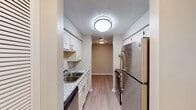 This single-floor residence offers a thoughtfully designed layout with a variety of functional spaces finished with consistent, modern detailing throughout. The galley-style kitchen is efficiently organized, featuring white shaker-style cabinetry with brushed nickel hardware, granite-look countertops, a double stainless steel sink, stainless steel appliances including a refrigerator and range, and wood-look plank flooring underfoot. A textured ceiling and recessed flush-mount lighting complete the space.

The open living area flows naturally from the kitchen, showcasing rich, dark wood-style flooring that adds warmth and contrast to the neutral taupe walls and bright white trim. A connected secondary living or dining area features lighter wood-tone flooring, offering a seamless yet distinct transition between spaces. Both areas are well-lit and spacious, with clean lines and a bright, open ambiance.

The bedrooms are carpeted for comfort, with neutral walls, textured ceilings, and windows fitted with horizontal blinds that allow for natural light. The rooms are generously proportioned and provide a calm, restful environment.

The bathroom is clean and functional, featuring light wood-look tile flooring, a white vanity with under-cabinet storage, a full tub-shower combination, and brushed nickel fixtures and hardware throughout — all contributing to a cohesive, move-in-ready aesthetic.