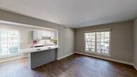 Located at 910 Shellbrook Ct in Raleigh, NC, this one-bedroom, one-bathroom residence offers a well-organized single-floor layout with a thoughtful blend of modern finishes and practical design. The open-concept living and dining area is anchored by rich, dark hardwood-style flooring and neutral gray walls, with a large multi-pane window that draws in generous natural light and frames views of the surrounding greenery. The kitchen is a standout feature, designed as a galley-style space with gray shaker cabinetry, marble-style countertops, a subway tile backsplash, skylights, and black stainless steel appliances including a refrigerator, range, and microwave. A pass-through counter connects the kitchen to the dining and living area, enhancing the open feel. The bedroom is a comfortable, well-proportioned room finished with plush carpeting, a ceiling fan, a window with outdoor views, and a spacious reach-in closet with double doors. The bathroom features a white shaker-style vanity with an undermount sink, a large mirror with overhead lighting, and hardwood-style flooring. Additional spaces include a utility room, hallway, and two closets, providing ample storage throughout.