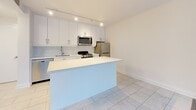 Located on Avenue Road in Toronto's desirable Midtown neighbourhood, this well-appointed one-bedroom, one-bathroom unit offers a thoughtfully designed layout with clean, modern finishes throughout. The entrance opens into a bright, airy interior featuring light-toned luxury vinyl plank flooring that flows through the main living areas.

The open-concept kitchen is a standout feature, showcasing white shaker-style cabinetry, a subway tile backsplash, white quartz countertops, a central island, and stainless steel appliances including a refrigerator, stove, and over-the-range microwave. Track lighting overhead adds a contemporary touch. The kitchen flows seamlessly into the combined dining and living area, which is bathed in natural light from large floor-to-ceiling windows dressed with vertical blinds. A door leads directly to the private balcony, offering pleasant views of the surrounding mature tree canopy.

The bedroom is a comfortable, well-proportioned space with the same warm flooring, neutral walls, and a mirrored sliding-door closet. Additional storage is provided by two closets throughout the unit. The bathroom features a full soaker tub and shower combination with elegant marble-effect tile surround and matching floor tiles. Light tile flooring in the entrance and kitchen areas completes the cohesive aesthetic of this move-in-ready home.