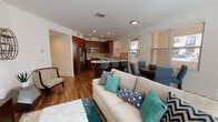 Located at 11056 Telegraph Rd in Ventura, California, this single-floor residence offers a thoughtfully designed open-concept layout that seamlessly connects the living, dining, and kitchen areas. Rich hardwood-style flooring flows continuously throughout the space, providing a cohesive and polished aesthetic.

The living room is generously proportioned, featuring large windows that invite natural light and provide views of the surrounding neighborhood. The open layout allows for flexible furniture arrangements, and recessed lighting supplements the natural illumination throughout.

The kitchen is a functional centerpiece, equipped with stainless steel appliances including a gas range, microwave, and dishwasher. Rich dark wood cabinetry contrasts elegantly with light quartz countertops and a stone tile backsplash. A peninsula with bar seating offers additional dining options alongside a dedicated dining area framed by multiple windows.

The bedrooms are comfortably sized, each featuring hardwood-style flooring, ample closet space, and window treatments for privacy. One bedroom includes a sliding glass door with outdoor access. Two full bathrooms each include a soaking tub with shower combination, rich wood vanities, and white tile surrounds, maintaining the residence's consistent design language.