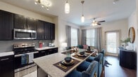 Located at 2250 Sara Jane Pkwy in Grand Prairie, Texas, this single-floor residence offers a thoughtfully designed open-concept layout that seamlessly connects the kitchen, dining, and living areas. The kitchen is a standout feature, showcasing bold dark cabinetry, granite countertops, a tile backsplash, stainless steel appliances, and a generously sized island with bar seating — ideal for both everyday meals and entertaining. Track lighting and pendant fixtures illuminate the space with a modern, layered look. The living area extends naturally from the kitchen, bathed in natural light from multiple windows and finished with wood-style flooring and a ceiling fan for year-round comfort. A welcoming entryway hallway, accented with wall art and a decorative mirror, sets an inviting tone upon arrival. The two bedrooms offer plush carpeting, ceiling fans, large windows, and ample space for restful retreats. Both full bathrooms are finished with dark vanity cabinetry, granite countertops, framed mirrors, and wood-style flooring — one featuring a full soaking tub and the other a clean, compact layout. Neutral wall tones throughout create a versatile backdrop that complements the home's contemporary design aesthetic.