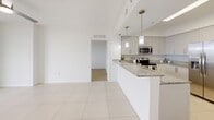 Located at 2101 Ludlam Rd in Miami, FL, this well-designed 2-bedroom, 2-bathroom residence offers a clean, modern aesthetic throughout. The open-concept living and dining area flows seamlessly from the kitchen, finished with large-format white tile flooring, and extends toward a glass-door balcony that invites natural light and outdoor views. The kitchen is thoughtfully appointed with white cabinetry, a mosaic tile backsplash, granite countertops, a peninsula with pendant lighting, and a full suite of stainless steel appliances including a range, microwave, refrigerator, and dishwasher. Both bedrooms feature light wood-look flooring, ceiling fans, and windows with views of the surrounding greenery. The spacious primary bedroom includes direct access to its own bathroom. Each bathroom is outfitted with tile flooring, a tub-shower combination with neutral tile surround, and granite vanity countertops. Two closets provide ample storage, complemented by a connecting hallway that ties the layout together efficiently. The overall ambiance is bright, airy, and move-in ready, reflecting a contemporary South Florida residential style.