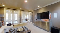 Located at 20 Ashton Village Dr in Westerville, Ohio, this single-story home offers a thoughtfully designed interior with a polished, contemporary aesthetic. The living area serves as a central gathering space, showcasing warm neutral wall tones, plush wall-to-wall carpeting, and crown molding that adds a touch of classic elegance. Recessed lighting illuminates the room evenly, creating a bright and inviting atmosphere. A sleek metallic media console anchors one wall, providing both style and functional storage, while a large flat-screen television is mounted above for an entertainment-focused layout. The space is distinguished by a set of classic white-framed French doors that open to an adjoining room, allowing natural light to flow freely between spaces and offering a sense of openness and connectivity. The adjoining room, visible through the glass panes, features hardwood flooring and additional natural light, suggesting a formal dining or sitting area. A tufted leather ottoman serves as a sophisticated centerpiece in the living space, complementing the room's refined, modern design. Overall, the home presents a seamless blend of classic architectural details and contemporary furnishings, delivering a comfortable and stylish living environment.