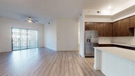 This well-appointed single-floor residence offers a thoughtfully designed open-concept layout that seamlessly connects the living, dining, and kitchen areas. Light hardwood-style flooring runs throughout the entire unit, lending a clean and cohesive aesthetic to every room.

The kitchen is a standout feature, showcasing rich dark-walnut shaker cabinetry that extends to the ceiling for ample storage, crisp white quartz countertops, a white subway tile backsplash, and a full suite of stainless steel appliances including a refrigerator with ice and water dispenser, range, microwave, and dishwasher. A large center island provides additional prep and seating space, while an open sightline connects the kitchen to the main living area.

The living area is generously proportioned, filled with natural light from sliding glass doors that lead to a balcony, and finished with a ceiling fan overhead. The bedrooms are bright and well-sized, with large windows inviting natural light and views of the outdoors. The bathroom features a tub-shower combo with white tile surround, a dark wood vanity with white countertop, and a separate water closet. A dedicated in-unit laundry area includes a full-size washer and dryer with overhead shelving. The overall ambiance is modern, clean, and move-in ready.