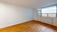 Located at 230 Oak St in Toronto's Corktown neighbourhood, this 2-bedroom, 1-bathroom unit offers a well-organized, single-floor layout designed to maximize functionality within a compact footprint. Warm-toned hardwood flooring runs consistently throughout the living areas and bedrooms, lending cohesion and a clean aesthetic to the space.

The living room is bright and open, featuring large windows and a glazed door that admit generous natural light and provide views of the surrounding neighbourhood. A wall-mounted radiator ensures efficient heating. The kitchen is fitted with white cabinetry, open upper shelving with built-in wine storage, light stone-toned countertops, and a stainless steel sink with a modern gooseneck faucet — a practical and tidy workspace.

The primary bedroom is a comfortable size, featuring a window with outdoor views and a radiator beneath it. The second bedroom includes a built-in double sliding-door closet and access to the hallway, making it versatile for various uses. Both rooms continue the hardwood flooring and clean white wall palette.

The bathroom is finished with large-format neutral grey tiles and features a soaker tub with a handheld showerhead and chrome fixtures, offering a straightforward and well-appointed bathing space. The hallway connects the rooms efficiently, contributing to the unit's practical flow.