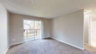 Located at 14095 SW Walker Rd in Beaverton, Oregon, this single-floor unit offers a practical and comfortable layout with a neutral color palette throughout. The living area is generously sized, featuring plush carpeting, textured ceilings, and warm beige walls that create a welcoming atmosphere. A sliding glass door floods the room with natural light and opens directly onto a wood-railed deck, providing pleasant outdoor views of the surrounding greenery. A wall-mounted thermostat and a structural column add functional and architectural character to the space. The open layout connects the living area to the kitchen, which is equipped with white cabinetry, laminate countertops, a stainless steel sink, and white appliances including a range. Ample upper and lower cabinet storage makes the kitchen both efficient and practical. A hallway leads to the additional rooms, including a full bathroom appointed with a shower-tub combination, chrome fixtures, and clean white finishes. The overall design is straightforward and functional, with consistent finishes and neutral tones carried throughout, making the space move-in ready and easy to personalize.