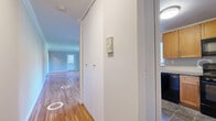 Located in Summit, NJ, this well-appointed 2-bedroom, 2-bathroom residence offers a thoughtfully laid-out single-floor plan with a clean, modern aesthetic throughout. Warm hardwood flooring flows continuously through the living room, hallway, and both bedrooms, lending a cohesive and inviting feel to the space.

The combined kitchen and living room area provides a functional hub for daily life. The kitchen features warm wood cabinetry, dark granite countertops, tile flooring, and black appliances including a full-size refrigerator and dishwasher, along with a window that brings in natural light. Crown molding accents the living area, adding a refined architectural detail.

The primary bedroom is generously sized, offering ample room for furnishings, and includes a large built-in closet with sliding doors. Both bedrooms feature windows with outdoor views and wall-mounted HVAC units for individual climate control.

The two bathrooms are notably upgraded, showcasing floor-to-ceiling marble-look tile, gray vanities with marble countertops, and chrome fixtures. One bathroom features a walk-in glass-enclosed shower, while the other includes a soaking tub-shower combination—both finished to a high standard.

A central hallway connects all rooms efficiently, completing this well-organized and move-in-ready residence in desirable Summit, NJ.