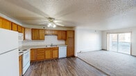 This single-floor unit offers a practical and well-organized layout designed for comfortable everyday living. The kitchen is a standout space, featuring warm oak cabinetry that extends to the ceiling for generous storage, light-colored countertops, wood-look vinyl flooring, and white appliances including a refrigerator, range, microwave, and dishwasher. A ceiling fan with integrated lighting adds both function and airflow to the kitchen area, which flows openly into the adjacent living space. The living area is carpeted and bright, with a sliding glass door providing direct access to a private balcony that offers views of the surrounding neighborhood.

The bedrooms are carpeted and feature baseboard heating, with one room including a window that brings in natural light. Neutral wall tones throughout create a clean, move-in-ready atmosphere. The unit includes two bathrooms, both finished with wood-look vinyl flooring and oak cabinetry. One bathroom offers a walk-in shower with built-in wire shelving for added storage convenience, while the other provides a full tub and elongated vanity. A mirrored sliding-door closet offers additional storage near the kitchen area. Textured ceilings are present throughout most of the unit.