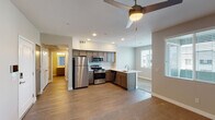 This single-floor residence offers a well-organized layout designed for comfortable, everyday living. The open-concept kitchen and living area forms the heart of the unit, where wood-look hard flooring connects the two spaces seamlessly. The kitchen is outfitted with dark-toned cabinetry, light quartz-style countertops, stainless steel appliances including a gas range, built-in microwave, and refrigerator, along with a peninsula featuring a deep undermount sink — an efficient and functional workspace. Recessed lighting illuminates the kitchen, while a ceiling fan serves the adjacent living area, which also benefits from natural light through window blinds. A keypad entry door is visible from the living space, adding a modern security feature. The bedrooms are carpeted and each includes a ceiling fan and windows with blinds providing outdoor views. One bedroom features sliding glass doors and direct access to a closet, while another includes a dedicated closet and direct access to an in-unit laundry room with a washer and dryer. The bathroom is cleanly appointed with a single-sink vanity, a large mirror, and a full soaking tub with shower. Throughout, the unit maintains a neutral color palette and consistent design language.