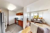 Located at 205 Dryden Rd in Ithaca, NY, this five-bedroom, two-bathroom single-floor unit offers a well-designed layout suited for shared living. The galley-style kitchen is outfitted with rich cherry wood cabinetry, dark granite countertops, tile flooring, and stainless steel appliances, opening seamlessly into the combined dining and living area. The living room features warm hardwood floors, wall sconce lighting, and large windows that fill the space with natural light and provide sweeping views of the Ithaca hillside. The adjacent dining nook benefits from the same panoramic windows, creating a bright and inviting atmosphere. Five individually accessed bedrooms offer carpeted floors, individual windows with exterior views, and dedicated closets. The two bathrooms are finished consistently with the rest of the unit, featuring tile flooring, granite-topped vanities with cherry wood cabinetry, and medicine cabinet mirrors. A connecting hallway ties the bedrooms and common areas together efficiently. With four closets distributed throughout, the unit provides ample storage. The cohesive design elements — granite surfaces, cherry wood finishes, and neutral walls — create a consistent and functional aesthetic throughout the entire space.