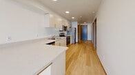Located at 2955 NE 11th St in Renton, WA, this one-bedroom, one-bathroom residence offers a thoughtfully designed single-floor layout with a clean, modern aesthetic throughout. Light-toned hardwood flooring flows through the main living areas, complemented by bright white walls and recessed lighting that create a fresh, airy atmosphere.

The kitchen is well-appointed with light wood cabinetry, white quartz countertops, a peninsula for additional prep space, and a full suite of stainless steel appliances including an electric range, over-the-range microwave, dishwasher, and refrigerator. It opens toward the living area, promoting an open and connected feel.

The bedroom is a comfortable, carpeted retreat featuring a sliding double-door closet, a window with natural light, and a second closet for additional storage. The bathroom is clean and modern, outfitted with a light wood vanity, quartz countertop, large mirror, and wood-look flooring.

A dedicated in-unit laundry area with a Whirlpool washer and dryer adds everyday convenience. The unit also includes a private balcony accessible via a glass-paneled door, providing outdoor space. With two closets and practical storage throughout, this residence offers a well-rounded and functional living environment.