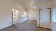 This 1-bedroom, 1-bathroom residence is thoughtfully laid out across a single floor, offering a comfortable and functional living environment. The open-concept living and dining area greets residents upon entry, featuring vaulted ceilings, neutral carpet flooring, and a ceiling fan that enhances the airy feel of the space. A tiled fireplace anchors one end of the living area, adding warmth and character, while vertical blinds on multiple windows invite natural light throughout.

The kitchen is positioned adjacent to the living area and is separated by a convenient breakfast bar peninsula. It features white cabinetry with ample upper and lower storage, a built-in electric range, refrigerator, and a sink — all efficiently arranged for ease of use.

The spacious primary bedroom offers generous square footage, plush carpeting, and large windows with vertical blinds that provide natural light and privacy. It is complemented by direct access to a walk-in closet equipped with double hanging rods and substantial storage capacity. The full bathroom includes a tub-shower combination, a vanity with storage drawers, and tile flooring.

Additional features include a dedicated laundry area and a tile-floored entryway. The overall design is clean, neutral, and move-in ready.