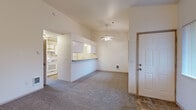 This 1-bedroom, 1-bathroom residence is thoughtfully laid out across a single floor, offering a comfortable and functional living environment. The open-concept living and dining area greets residents upon entry, featuring vaulted ceilings, neutral carpet flooring, and a ceiling fan that enhances the airy feel of the space. A tiled fireplace anchors one end of the living area, adding warmth and character, while vertical blinds on multiple windows invite natural light throughout.

The kitchen is positioned adjacent to the living area and is separated by a convenient breakfast bar peninsula. It features white cabinetry with ample upper and lower storage, a built-in electric range, refrigerator, and a sink — all efficiently arranged for ease of use.

The spacious primary bedroom offers generous square footage, plush carpeting, and large windows with vertical blinds that provide natural light and privacy. It is complemented by direct access to a walk-in closet equipped with double hanging rods and substantial storage capacity. The full bathroom includes a tub-shower combination, a vanity with storage drawers, and tile flooring.

Additional features include a dedicated laundry area and a tile-floored entryway. The overall design is clean, neutral, and move-in ready.