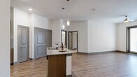 Located in Corinth, TX, this well-appointed 2-bedroom, 2-bathroom residence offers a thoughtfully designed single-level layout. The open-concept kitchen and living area serves as the heart of the home, showcasing warm wood-look plank flooring, recessed lighting, and pendant fixtures over a central island with a granite countertop and built-in sink. The kitchen is equipped with stainless steel appliances, medium-toned cabinetry, a tile backsplash, and ample storage. The living area flows seamlessly to a private balcony through glass French doors, allowing natural light to fill the space. Both bedrooms are carpeted and feature ceiling fans, windows with blinds, and dedicated closets, providing comfortable and functional retreats. The generously sized primary bedroom offers notable square footage for flexible furnishing arrangements. Each bathroom is finished with granite-topped wood vanities, large mirrors, and wood-look tile flooring. One bathroom includes a tub-shower combo, while the other features a walk-in tiled shower. Neutral wall tones throughout create a clean, cohesive aesthetic that complements both modern and traditional décor styles.