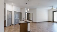 Located in Corinth, TX, this well-appointed 2-bedroom, 2-bathroom residence offers a thoughtfully designed single-level layout. The open-concept kitchen and living area serves as the heart of the home, showcasing warm wood-look plank flooring, recessed lighting, and pendant fixtures over a central island with a granite countertop and built-in sink. The kitchen is equipped with stainless steel appliances, medium-toned cabinetry, a tile backsplash, and ample storage. The living area flows seamlessly to a private balcony through glass French doors, allowing natural light to fill the space. Both bedrooms are carpeted and feature ceiling fans, windows with blinds, and dedicated closets, providing comfortable and functional retreats. The generously sized primary bedroom offers notable square footage for flexible furnishing arrangements. Each bathroom is finished with granite-topped wood vanities, large mirrors, and wood-look tile flooring. One bathroom includes a tub-shower combo, while the other features a walk-in tiled shower. Neutral wall tones throughout create a clean, cohesive aesthetic that complements both modern and traditional décor styles.