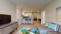 Located in the Gateway community of East Lyme, Connecticut, this single-floor residence showcases a thoughtfully designed open-concept layout with contemporary finishes throughout. Light-toned hardwood flooring flows through the main living areas, connecting the living room, dining area, and kitchen seamlessly.

The kitchen is a standout feature, equipped with stainless steel appliances, a tile backsplash, dark lower cabinetry contrasted by crisp white upper cabinets, and a granite-topped island with bar seating. Recessed lighting illuminates the space efficiently. The living room benefits from a large sliding glass door that invites natural light and provides views of the surrounding greenery.

A dedicated dining area sits adjacent to a convenient in-unit laundry closet housing a stacked washer and dryer. The bedrooms are carpeted for comfort and feature multiple windows overlooking outdoor scenery, creating a calm, restful atmosphere.

Two bathrooms serve the residence: one includes a granite-topped vanity and a combination tub and shower with safety grab bars, while the second features a walk-in glass-enclosed shower and matching granite countertops with tile flooring. Both bathrooms are finished with dark wood cabinetry for a cohesive, polished look throughout the home.