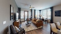 Located at 930 Jones Franklin Rd in Raleigh, NC, this single-floor residence offers a thoughtfully designed layout with contemporary finishes throughout. The entry features a built-in mudroom with a cushioned bench, coat hooks, and open shelving, providing a practical and welcoming transition into the living space. Rich hardwood-style flooring flows throughout the main areas, complementing the neutral color palette.

The kitchen is well-equipped with stainless steel appliances, including a refrigerator, range, and microwave, alongside white shaker cabinetry extending to the ceiling, a dark tile backsplash, and a large island with a undermount sink and pendant lighting. The adjacent dining area is bathed in natural light from a bank of large windows offering views of the surrounding area.

The living room features a ceiling fan, large windows with outdoor access, and a warm, layered design aesthetic. The primary bedroom offers a sophisticated atmosphere with muted tones, while an additional bedroom provides natural light through a sizable window. Both bathrooms include marble-style tile flooring, white vanity cabinetry, and well-lit mirrors, with the primary bath featuring a walk-in closet.