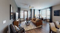 Located at 930 Jones Franklin Rd in Raleigh, NC, this single-floor residence offers a thoughtfully designed layout with contemporary finishes throughout. The entry features a built-in mudroom with a cushioned bench, coat hooks, and open shelving, providing a practical and welcoming transition into the living space. Rich hardwood-style flooring flows throughout the main areas, complementing the neutral color palette.

The kitchen is well-equipped with stainless steel appliances, including a refrigerator, range, and microwave, alongside white shaker cabinetry extending to the ceiling, a dark tile backsplash, and a large island with a undermount sink and pendant lighting. The adjacent dining area is bathed in natural light from a bank of large windows offering views of the surrounding area.

The living room features a ceiling fan, large windows with outdoor access, and a warm, layered design aesthetic. The primary bedroom offers a sophisticated atmosphere with muted tones, while an additional bedroom provides natural light through a sizable window. Both bathrooms include marble-style tile flooring, white vanity cabinetry, and well-lit mirrors, with the primary bath featuring a walk-in closet.