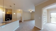 Located at 1202 Evans Rd in San Antonio, TX, this single-story residence offers a well-designed layout with a comfortable, neutral aesthetic throughout. The open living area is finished with plush carpet and crown molding, and is anchored by a ceiling fan. Arched doorways connect the main living space to a hallway leading to the private areas of the home, adding an architectural touch that enhances the flow of the floor plan. A sliding glass door provides access to an outdoor balcony, bringing in natural light and views of the surroundings.

The kitchen is outfitted with light wood cabinetry, granite-style countertops, and black appliances including an electric range, built-in microwave, and refrigerator. Wood-look flooring in the kitchen adds warmth and contrast to the carpeted living areas. A breakfast bar with pendant lighting connects the kitchen to the living space, making it ideal for casual dining.

The bedrooms are carpeted and feature ceiling fans and generous closet space with built-in shelving. The bathrooms are finished with wood-look flooring, warm wood vanity cabinetry, granite-style countertops, and a tiled tub-shower combination. The warm, neutral color palette used throughout the home creates a cohesive and inviting atmosphere.