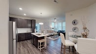 This single-floor residence at 4109 offers a thoughtfully designed open-concept layout that seamlessly connects the kitchen, dining, and living areas. The kitchen is a standout feature, showcasing rich dark-espresso cabinetry, white quartz countertops, stainless steel appliances, and a central island with bar seating illuminated by pendant lighting. Wood-look plank flooring flows throughout the main living areas, complementing the neutral color palette.

The living room is bright and welcoming, benefiting from multiple large windows that invite abundant natural light. A ceiling fan adds comfort, while the open sightlines to the kitchen create an ideal space for entertaining.

The bedrooms are carpeted and well-sized, each offering windows that enhance the airy atmosphere. An additional flex room with a wall of windows serves well as a home office or sitting area. The bathroom features dark cabinetry paired with white countertops, a dual-sink vanity, and a full soaking tub with a shower. Throughout the residence, a consistent design language of dark wood tones against crisp white surfaces creates a modern, polished aesthetic.