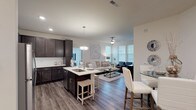 This single-floor residence at 4109 offers a thoughtfully designed open-concept layout that seamlessly connects the kitchen, dining, and living areas. The kitchen is a standout feature, showcasing rich dark-espresso cabinetry, white quartz countertops, stainless steel appliances, and a central island with bar seating illuminated by pendant lighting. Wood-look plank flooring flows throughout the main living areas, complementing the neutral color palette.

The living room is bright and welcoming, benefiting from multiple large windows that invite abundant natural light. A ceiling fan adds comfort, while the open sightlines to the kitchen create an ideal space for entertaining.

The bedrooms are carpeted and well-sized, each offering windows that enhance the airy atmosphere. An additional flex room with a wall of windows serves well as a home office or sitting area. The bathroom features dark cabinetry paired with white countertops, a dual-sink vanity, and a full soaking tub with a shower. Throughout the residence, a consistent design language of dark wood tones against crisp white surfaces creates a modern, polished aesthetic.