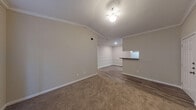 This single-floor residence offers a comfortable and practical layout designed to maximize livability. The main living area is finished with plush carpet and crowned with elegant crown molding, while a ceiling fan provides both light and airflow. The space flows naturally toward a dedicated dining or secondary living area, separated by a peninsula countertop with a pass-through opening to the kitchen — ideal for casual dining or entertaining. A set of French doors with blinds fills this area with natural light and provides outdoor access.

The kitchen is well-equipped, featuring warm wood cabinetry, dark speckled countertops, and a full suite of appliances including an electric range, over-the-range microwave, and refrigerator. Wood-look flooring runs throughout the kitchen, adding a clean, durable finish.

The bedrooms are carpeted and bright, each equipped with a ceiling fan and window with blinds for light control. A generously sized walk-in closet with wire shelving provides ample storage.

Both bathrooms mirror each other in style, featuring wood-look vinyl flooring, warm wood vanity cabinetry, white countertops, and a tub-shower combination. The overall aesthetic throughout the space is neutral and move-in ready, with consistent warm-toned walls and white trim detailing.